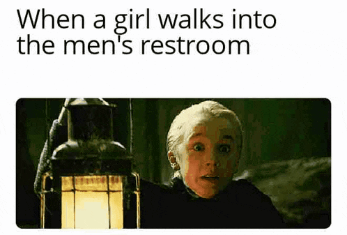 a girl is walking into the men 's restroom while holding a lamp .