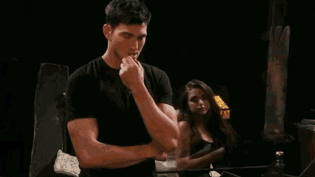 a man in a black shirt is standing in front of a woman