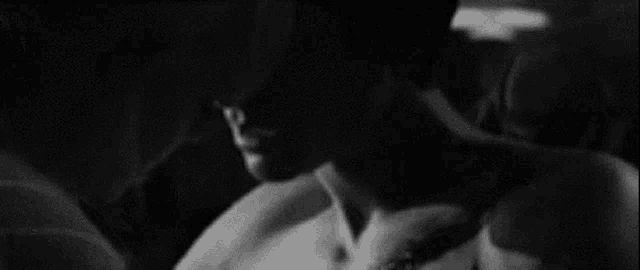 a black and white photo of a man and woman kissing .