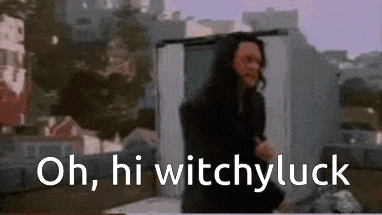 a man is standing in front of a building with the words oh , hi witchyluck written on the bottom .