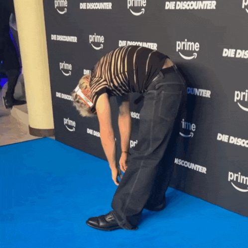 a man is bending over on a blue carpet that says prime on it