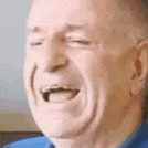 a close up of a man laughing with his eyes closed .