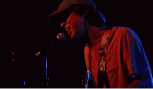 a man singing into a microphone while playing a guitar in front of a crowd