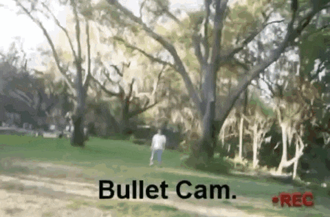 a man is walking through a park with a bullet cam in the foreground .