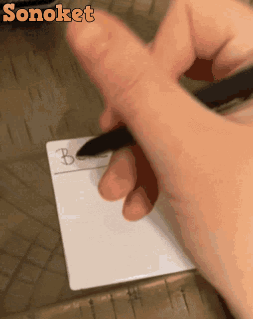 a person is writing on a piece of paper with the word sonoket on the top