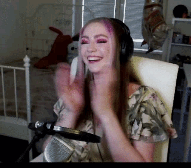 a woman wearing headphones and a floral shirt is sitting in front of a microphone