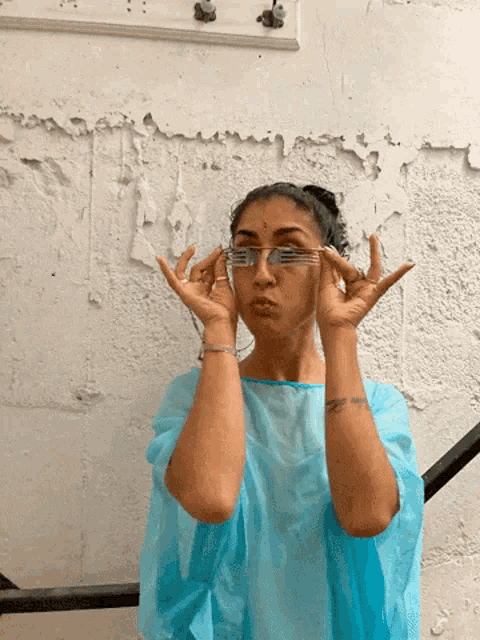 a woman wearing a blue shirt and glasses looks at the camera