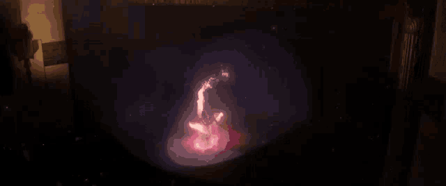 a person is standing in a dark room with a red light coming out of their mouth .