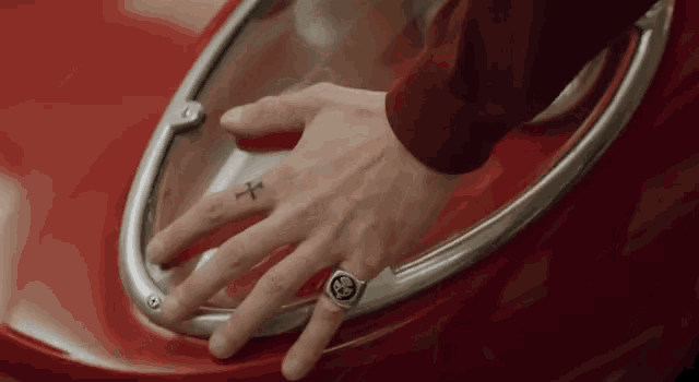 a close up of a person 's hand with a cross tattoo on their finger .