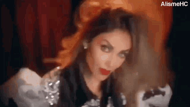 a woman with long hair and red lipstick is making a funny face in a blurry photo .