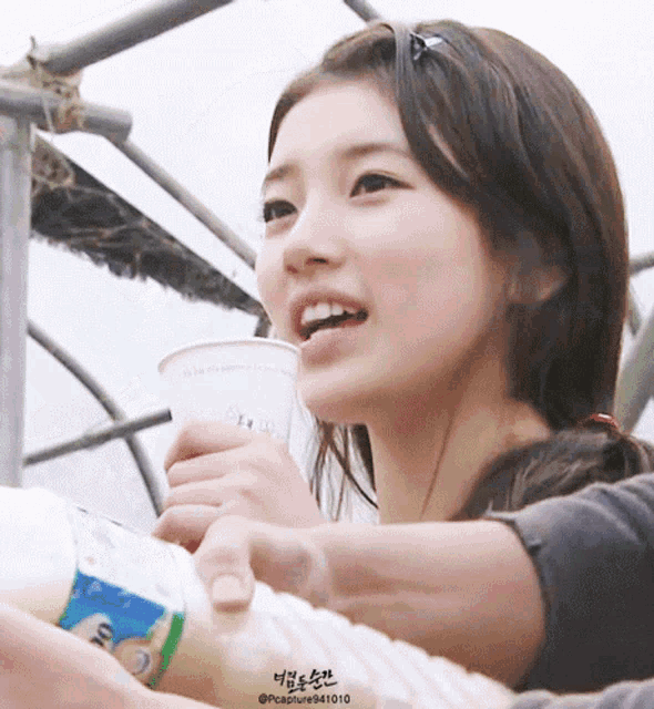 a close up of a woman holding a cup and a bottle with the name pccapture941010 on the bottom