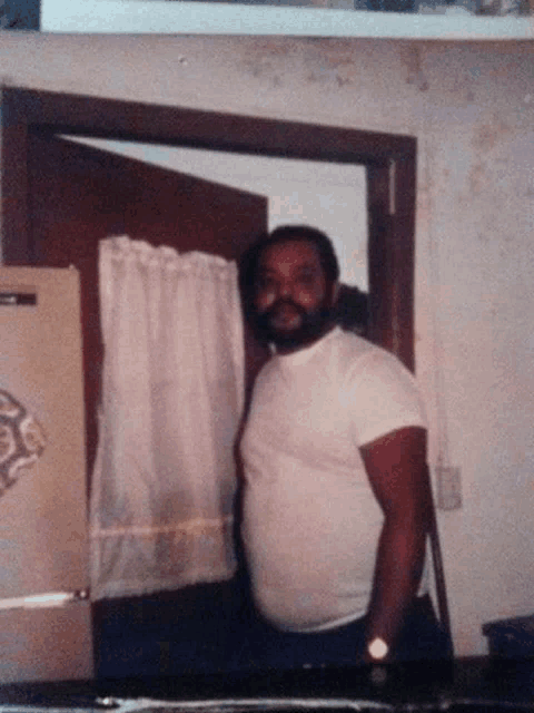 a man in a white shirt is standing in front of a refrigerator