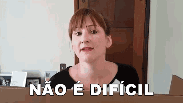 a woman is standing in front of a door with the words não e dificil written on her face .