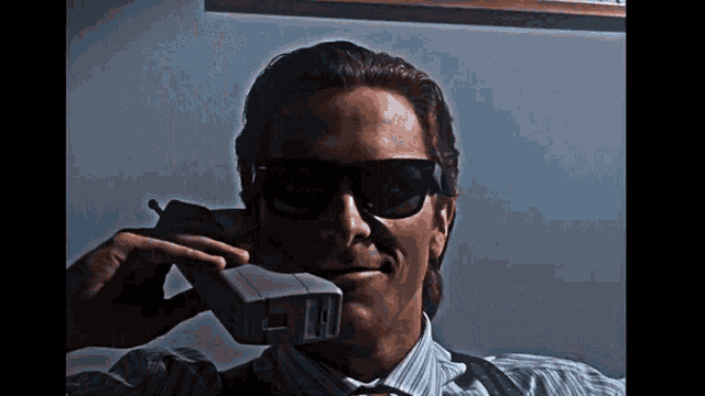 a man wearing sunglasses is talking on a cellphone