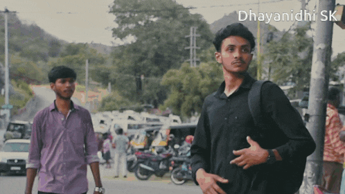 two men are walking down a street with the words dhayanidhi sk on the bottom right