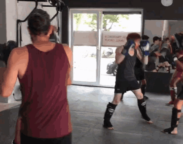 a group of people are boxing in a gym with a sign on the wall that says ' aerobics '