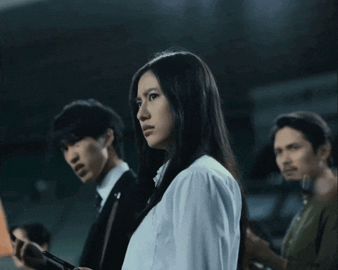 a woman in a white shirt looks down while a man in a suit looks at his phone