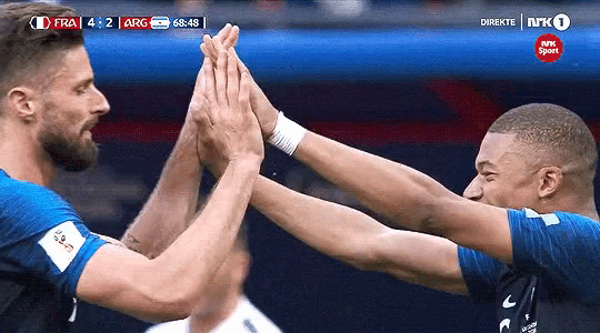 two soccer players giving each other a high five during a game sponsored by nrk