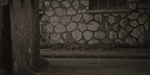 a woman in a black dress is running down a street with a gun .
