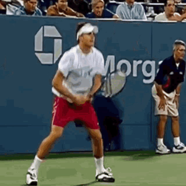a man is playing tennis in front of a wall that says morgan