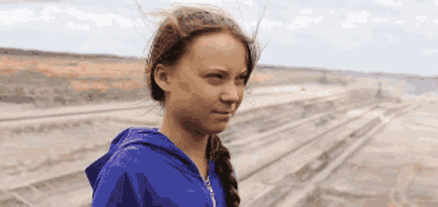 a girl in a blue hoodie is standing in a field