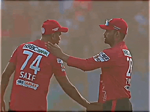a man wearing a red jersey with the number 74 on it shakes hands with another man