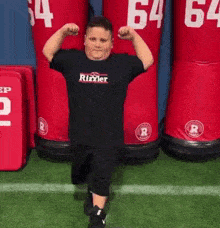 a young boy is flexing his muscles in front of a row of red mannequins with the number 64 on them