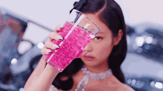 a woman holding a glass of pink liquid in her hand