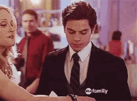 a man in a suit and tie is standing next to a woman with abc family written on the bottom of the screen