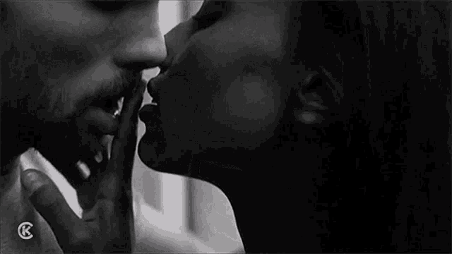 a black and white photo of a woman kissing a man 's neck .