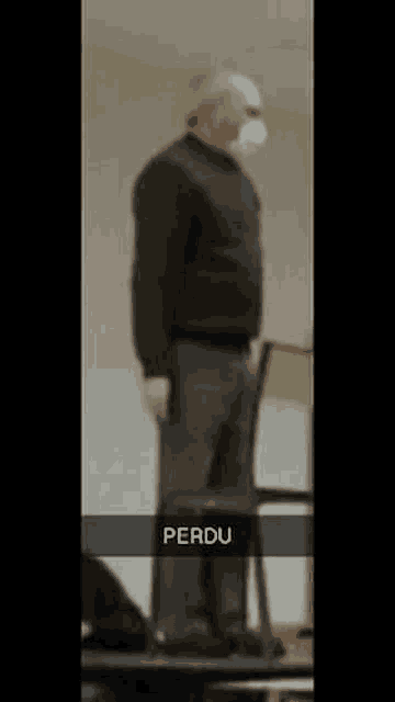 a man wearing a mask is standing in front of a chair in a room .