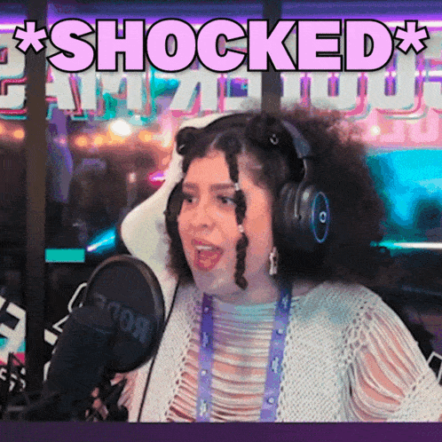 a woman wearing headphones stands in front of a microphone with the words " shocked " above her