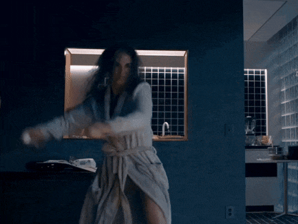 a woman in a bathrobe is dancing in front of a mirror