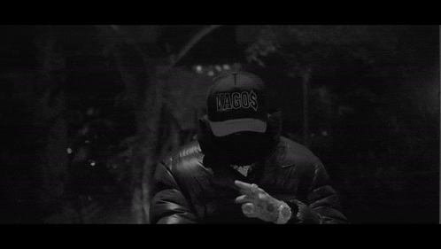 a black and white photo of a man wearing a lagos hat