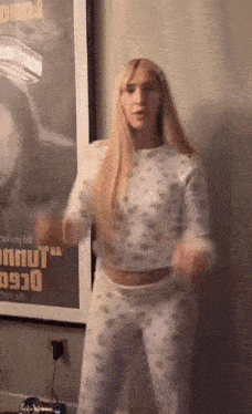a woman in pajamas is dancing in front of a framed poster that says ' nnut ' on it