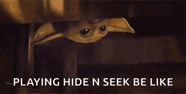a baby yoda is peeking out from under a wall .