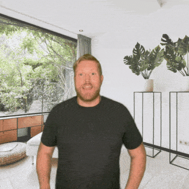 a man in a black shirt is standing in front of a large window