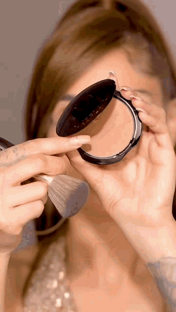 a woman is applying powder with a brush