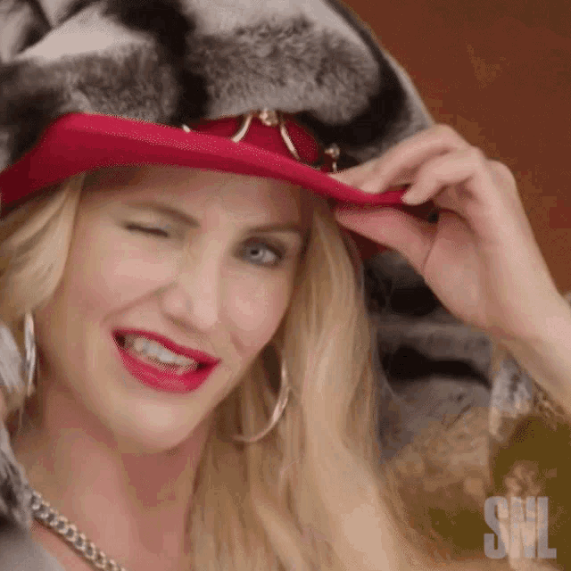 a woman wearing a fur coat and a red hat with snl written on the bottom right
