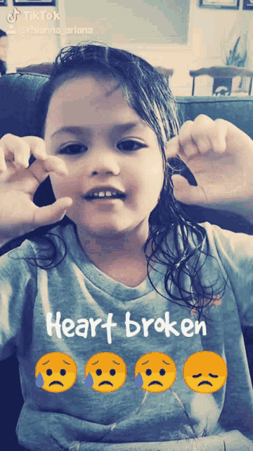 a little girl wearing a grey shirt that says heart broken