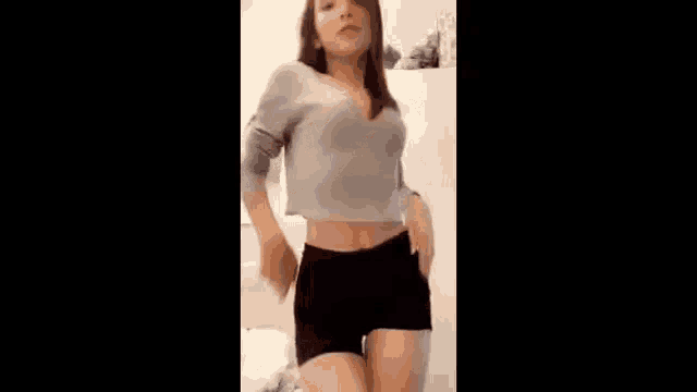 a woman wearing a sweater and shorts is standing in a room .