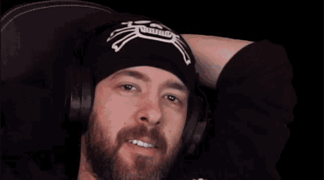 a man with a beard and headphones is sitting in a chair .