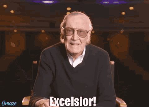 a man with glasses and a mustache is sitting in a chair and saying excelsior