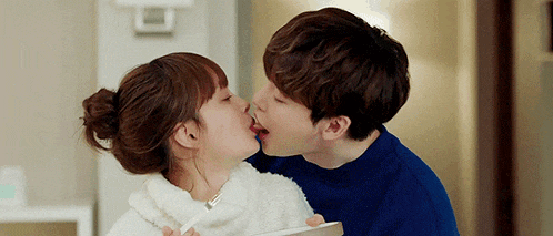 a man and a woman are kissing each other while holding a box .