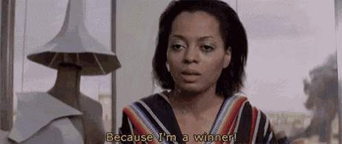 a woman is standing in front of a window and says `` because i 'm a winner ''