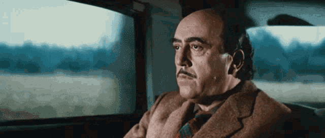 a man in a suit and tie is looking out a window