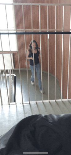 a woman in a black tank top is standing in a room