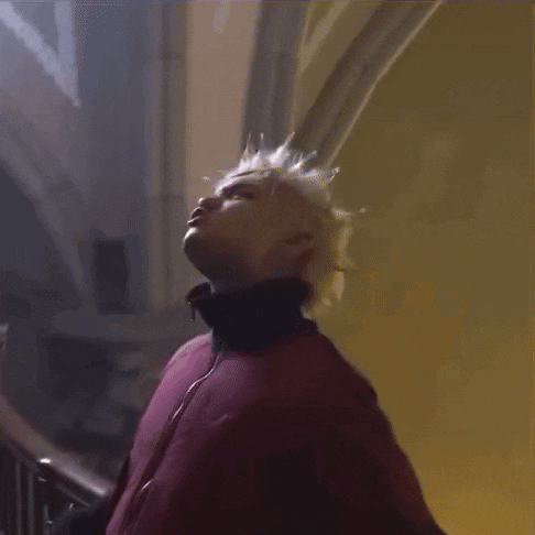 a man in a red jacket and black gloves is standing on a staircase with his arms in the air .
