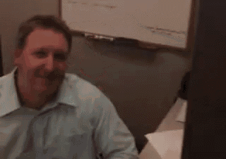 a man in a blue shirt is sitting at a desk in front of a computer .