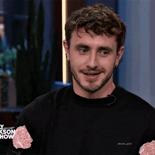 a man wearing a black shirt with roses on the sleeves is smiling